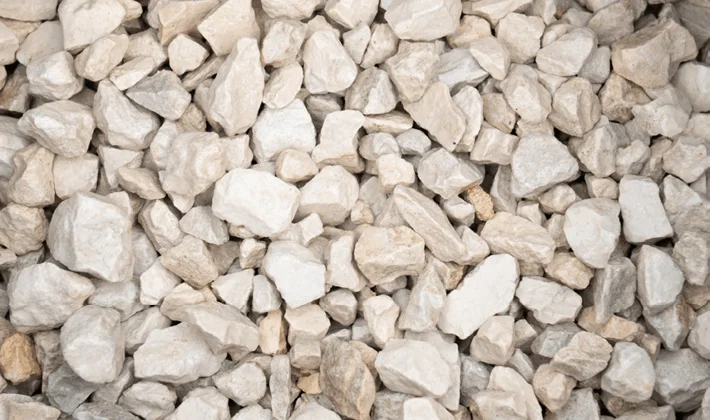 Buff-coloured clean limestone chippings displayed wet, graded from 10mm to 20mm.