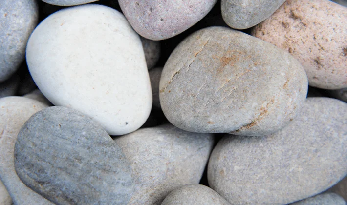 Loose display of multi-coloured, naturally rounded cobbles, showcased dry.