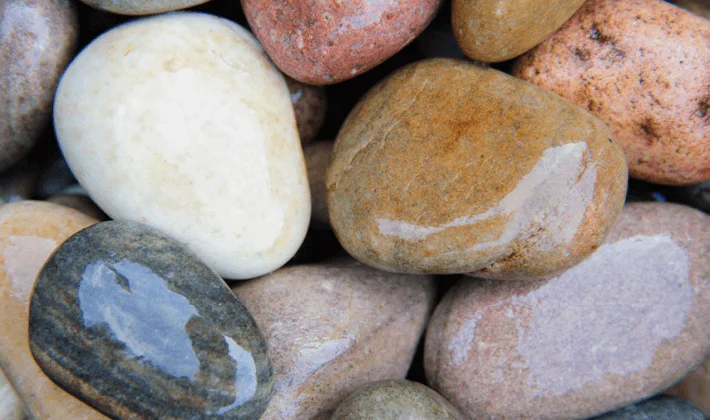 Loose display of multi-coloured, naturally rounded cobbles, showcased wet.