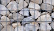 Gabion stone, containing irregularly shaped limestone, granite and ragstone rocks between 50mm and 200mm, displayed in a gabion stone basket.