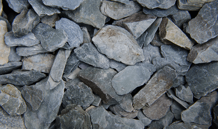 Loose display of green slate, containing green, blue and grey chippings, graded from 30mm to 50mm, showcased dry.