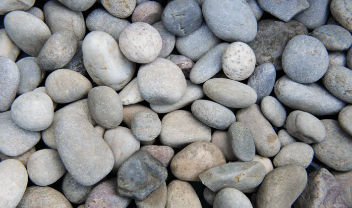 Naturally rounded, multi-coloured, river-washed pebbles, displayed dry.