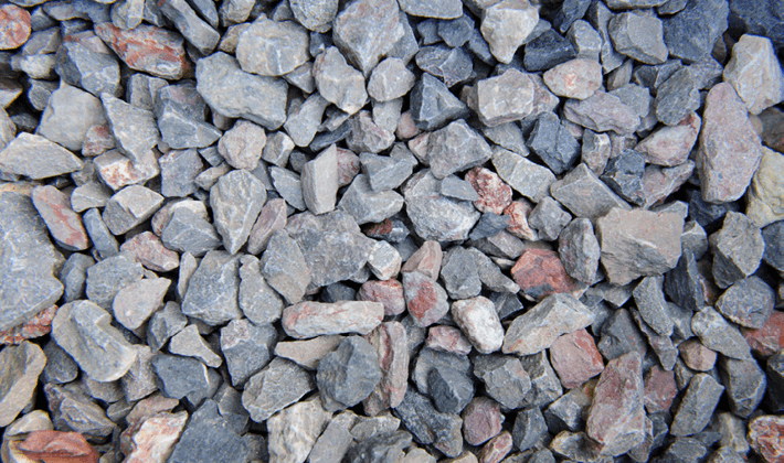 Loose permeable paving aggregate, presented dry, containing pink and grey angular limestone and granite.