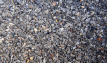 Permeable paving aggregate containing pink and grey angular limestone and granite, displayed wet.