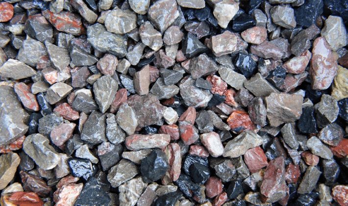 Loose permeable paving aggregate, presented wet, containing pink and grey angular limestone and granite.