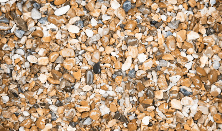 Loose display of pea shingle, a natural flint aggregate, graded from 4mm to 10mm, showcased wet.