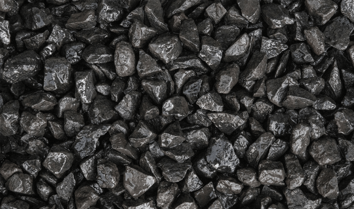 Loose display of black basalt, showcasing dark grey angular stones graded from 10mm to 20mm, presented in a wet condition.